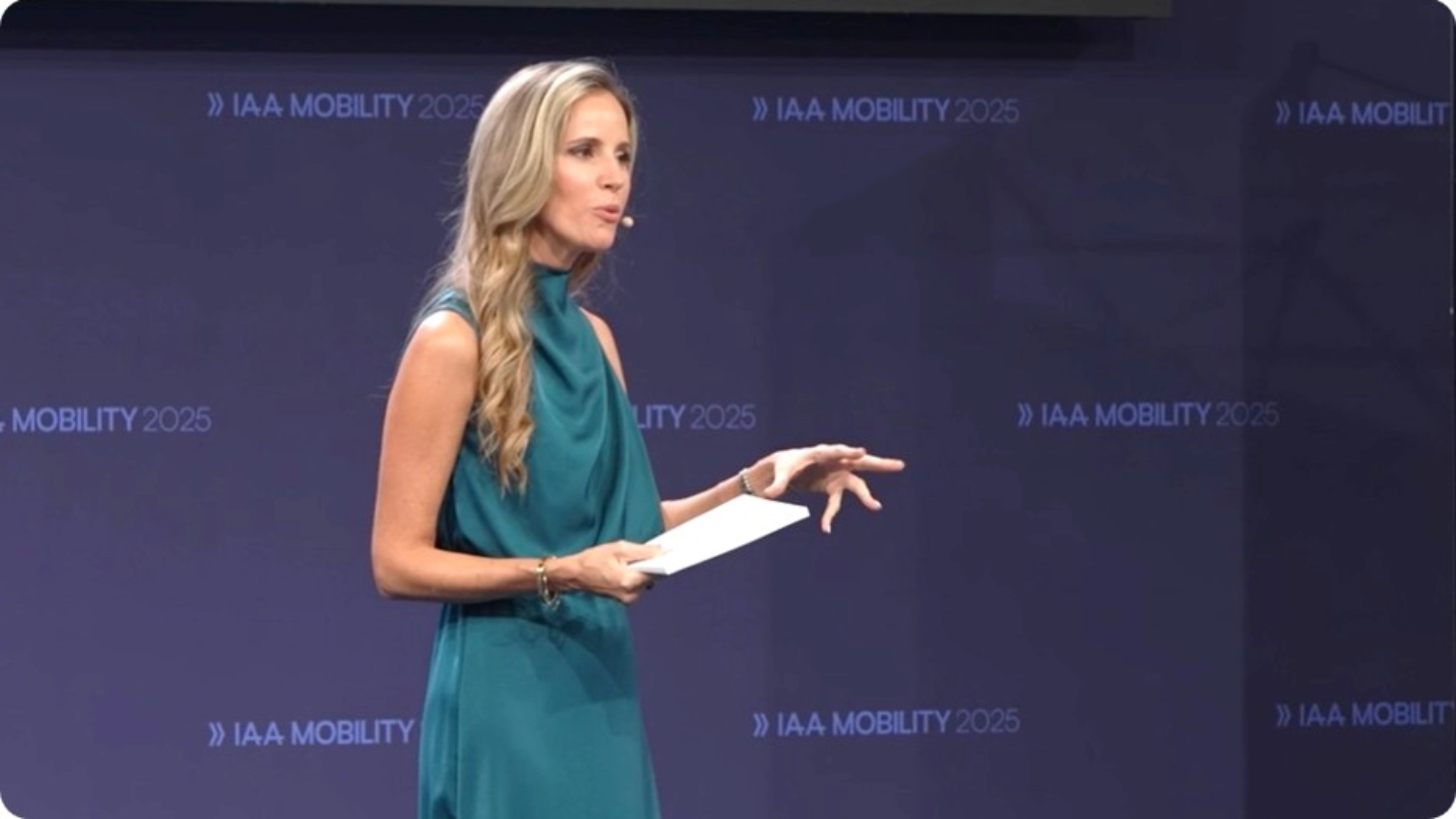 A speaker presents on stage at IAA Mobility 2025 while holding notes.