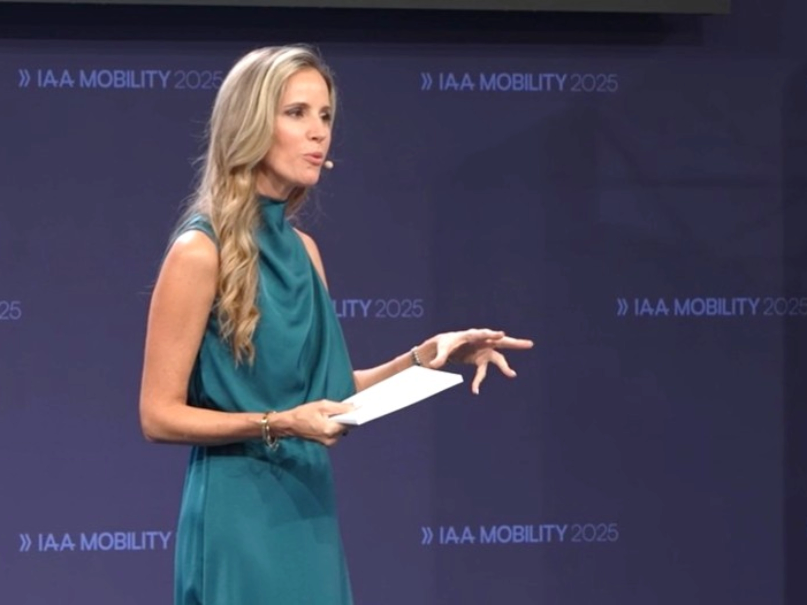 A speaker presents on stage at IAA Mobility 2025 while holding notes.